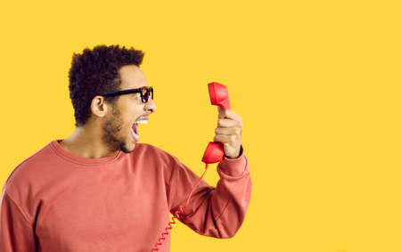 Side view man with angry face expression shouting at stupid call center tech support service line...