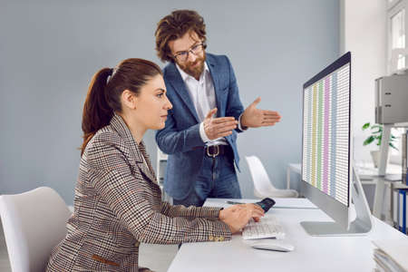 People working in office. Male manager talking to female trainee, giving advice and explaining...