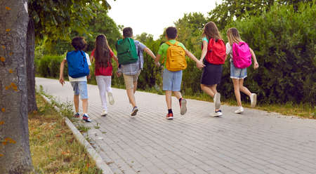 Happy students on their way to school. Group of children running to class. Several kids with...