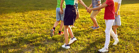 Little kids playing fun games outside. Happy boys and girls dancing round dance on green grass in...