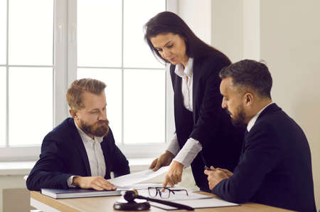 Diverse lawyers sit at desk at meeting talk discuss paperwork documents together. Men and women associates or partners speak on justice or legislation issues. Law and order concept.の写真素材