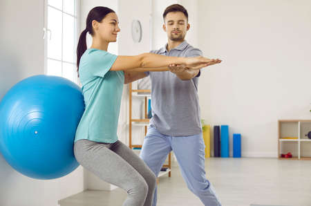 Rehabilitation therapy. Woman with back injury performs exercises with gymnastic ball during meeting...