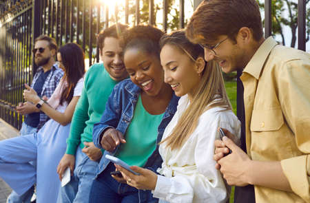 Happy young people enjoying both virtual and in real life communication. Cheerful multiethnic...