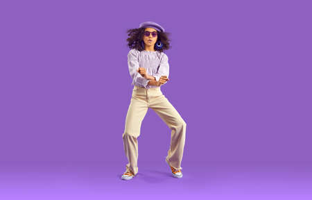 Child dancing. Confident African American girl with curly hair in trendy top, beige jeans, beret hat...