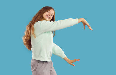 Cheerful carefree young woman listening to music, having fun and dancing joyfully. Caucasian girl in...