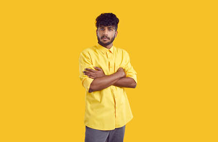 Portrait of serious indian guy with dissatisfied facial expression isolated on orange background....