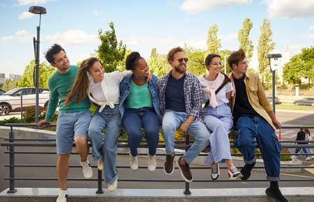 Group of stylish, cheerful and friendly multiracial men and women walking together in city center....