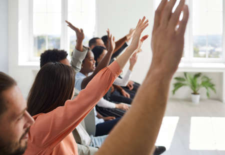 Diverse multiracial male female audience raising hands. Crowd of active mixed race multiethnic men...