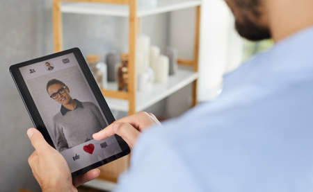 Man is going to give a like to womans photo in mobile dating app on smartphone screen. Single man looking for love and relationship online. Searching for romantic partner in social app concept.の写真素材