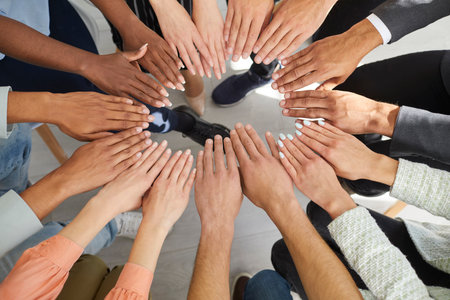 Diverse group of young people joining hands. Team of multicultural males and females with different...