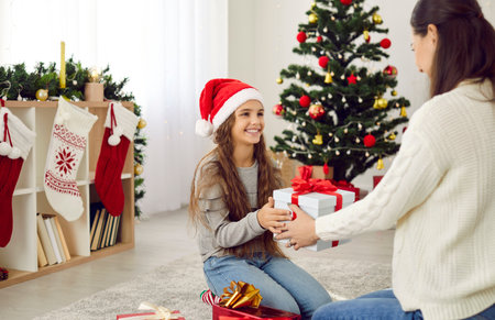 Loving young mother give present to excited little daughter congratulate with Christmas eve. Caring mom greeting happy small girl child with New Year winter holidays with wrapped gift box.の写真素材