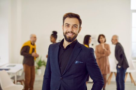 Portrait of successful smiling young Caucasian businessman in formal suit pose at workplace. Confident male boss or director forefront in office, show leadership and success. Employment concept.の写真素材
