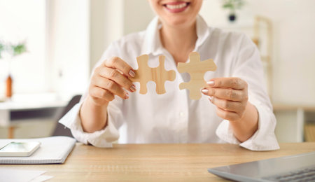 Solving the puzzle, piece by piece. Close up of two wooden puzzle pieces in hands of unrecognizable...