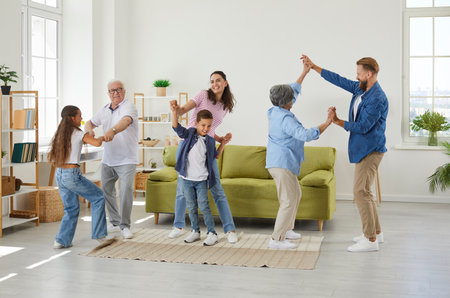 Family weekend. Funny family members of different generations having fun listening music and dancing in room at home. Young and old people together with small children spend time together.の写真素材