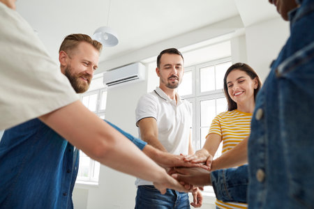 Team of cheerful people joining hands to show concept of teamwork and achieving success together....