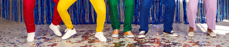 Legs of five unknown men and women who are dancing on colored confetti at disco party. Panoramic...