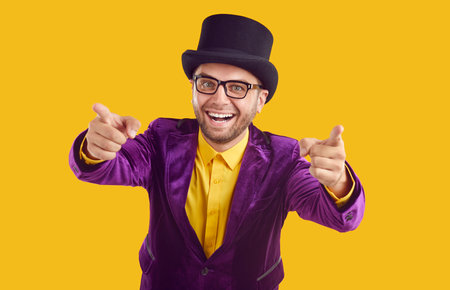 Happy laughing unshaved showman in glasses, black hat, yellow shirt, purple velvet jacket is...