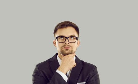 Serious businessman with doubtful uncertain facial expression hesitates to make important decision....
