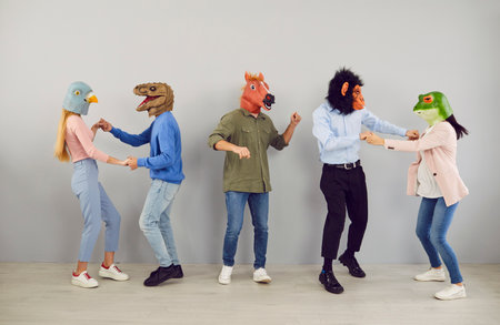 Group of five strange people in animal disguise dancing and having fun together. Team of young men and women wearing funny wacky animal masks having fun at crazy partyの写真素材