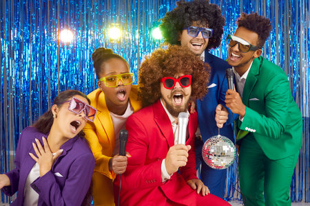Group of cheerful, funny and creative young people having fun at karaoke party night. Multiracial...