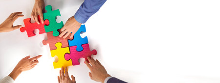 Business team matching jigsaw puzzle parts. Young people connect colorful red, green, pink, blue,...