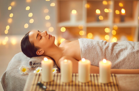 Young pretty woman lying with closed eyes alone relaxing during spa procedure in salon on massage couch at wellness center. Girl enjoying health therapy treatment. Wellness and beauty day concept.の写真素材