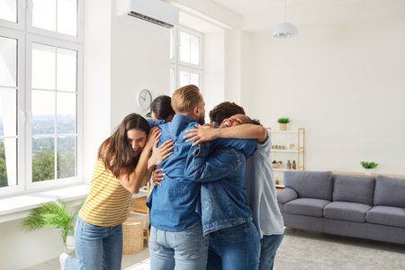 Its good to see you all again. Friends meet after long separation. Joyful friends standing and hugging. Group of diverse people having fun and congratulating each other on happy life eventの写真素材