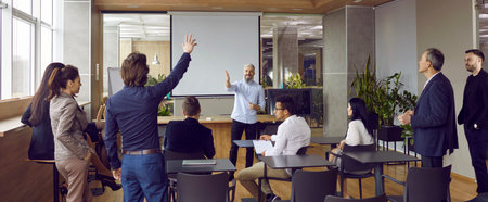 Group of adult students having class with business teacher in modern office interior. Man raises his hand to answer question, ask something or make interesting suggestion. Team training concept bannerの写真素材