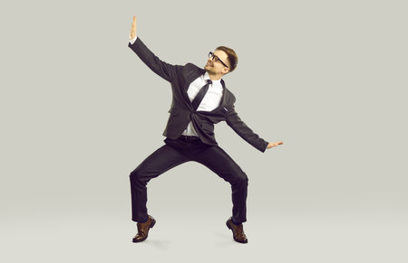 Work day is over lets go home. Happy office worker having fun because weekend starts now. Full body length cheerful joyful funny excited business man in suit dancing isolated on light gray backgroundの写真素材