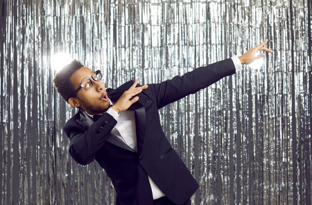 Happy young ethnic guy moving to music and having fun at party. Funny confident energetic mixed race...