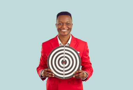 Happy African man with shooting target isolated on light background. Studio shot of smiling handsome...