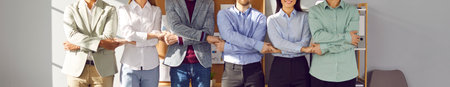 Cropped shot of a team of happy young business people standing in a row and holding hands. Corporate...