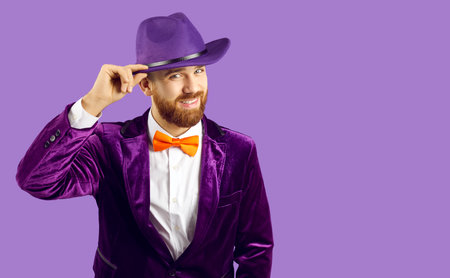 Portrait of smiling man in jacket and hat isolated on purple studio background look at camera. Happy male performer or party guy in carnival suit meet audience. Entertainment concept.の写真素材