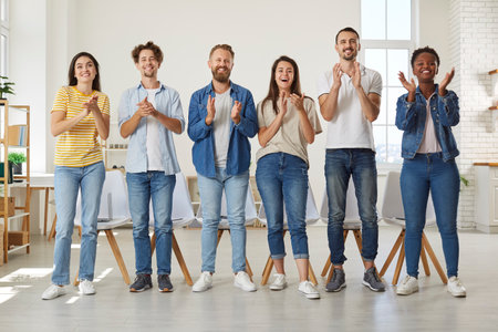 Friendly multiracial people in casual clothes stand in row and applaud looking at you. Group of...