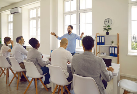 Young cheerful and confident man makes presentation about business ideas in front of business...
