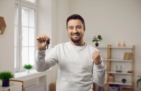 Portrait of a young happy smiling attractive man with the keys in his hands at office or at home....