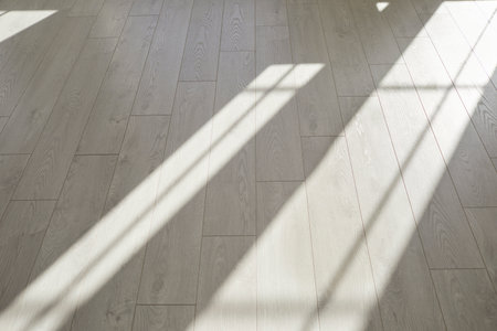 Clean, empty parquet or laminate flooring background. Perfectly shaped rectangle grey hard wood strips lit by bright sunlight from windows in minimalist interior inside modern house. No people, nobodyの写真素材