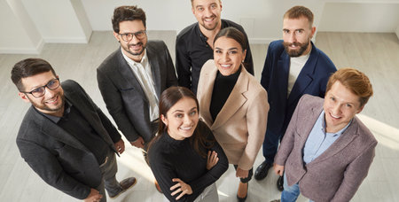 View from above of happy, successful business people. Smiling office colleagues or partners looking up at camera. Top view of professional business team in formal wearの写真素材