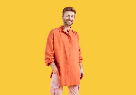Portrait of happy cheerful bearded young man smiling at camera. Positive relaxed man in casual wear posing isolated over yellow studio background with copy spaceの写真素材