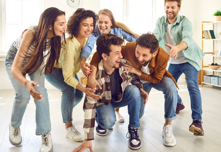 Portrait of a funny young happy overjoyed group of people friends students having fun playing at home and laughing enjoying time together. Party, friendship and team games concept.の写真素材