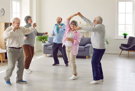 Full length portrait of a group of happy smiling senior people men and women having fun and dancing enjoying activities in retirement home together. Leisure time in nursing home concept.の写真素材