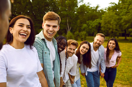 Portrait of friends having fun and laughing while walking in park on warm summer day. Multiracial...