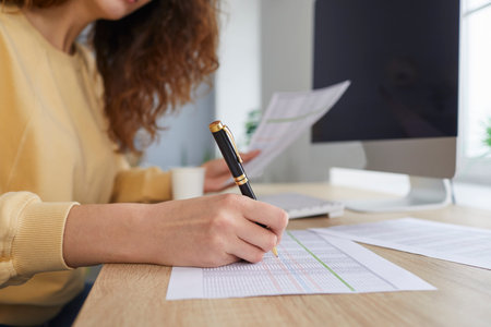 Lady accountant working with balance sheets in office. Female worker checking columns on paper business spreadsheet, reviewing enterprise loss and profit figures. Close up. Budget concept backgroundの写真素材