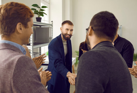 Two successful businessmen shaking hands at meeting in modern office. Smiling business colleagues applauding them. Partnership approval, cooperation, successful deal conceptの写真素材