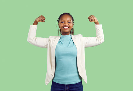 Young African woman demonstrates her strength. Happy active strong African American model standing...