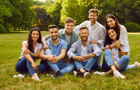 Portrait of seven happy carefree young male and female friends in summer park. Cheerful Caucasian...