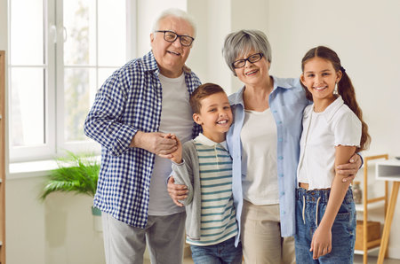 Portrait of a happy grandparents with their grandchildren boy and girl standing in the living room...