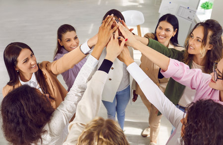 Group of smiling young women doing high five gesture. Cropped shot of cheerful successful business...