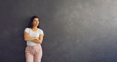 Banner background with confident attractive young woman in casual outfit standing with her arms...