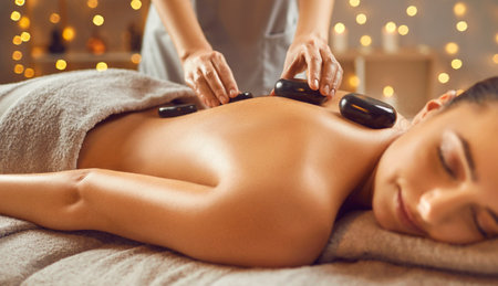 Young woman enjoying having hot stone therapy and spa treatment. Beautiful relaxed girl lying on...